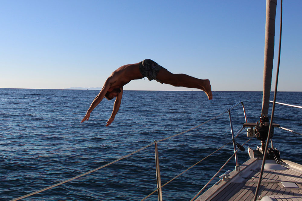 ragazzo che si tuffa di testa in mare da una barca